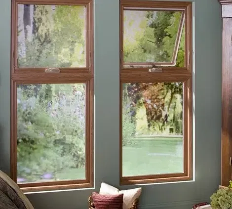 A pair of wooden-framed windows displays a lush garden view. Sunlight filters through, casting a serene glow inside. Cushions rest below the windowsill.