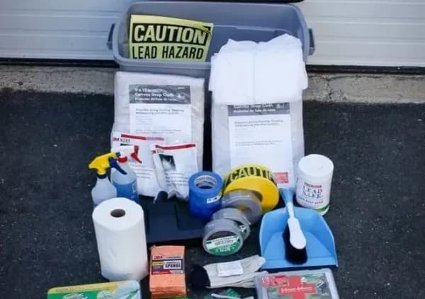 A lead hazard safety kit is displayed, including a caution sign, protective clothing, dust mask, cleaning supplies, tape, and scrub brush, conveying preparedness.